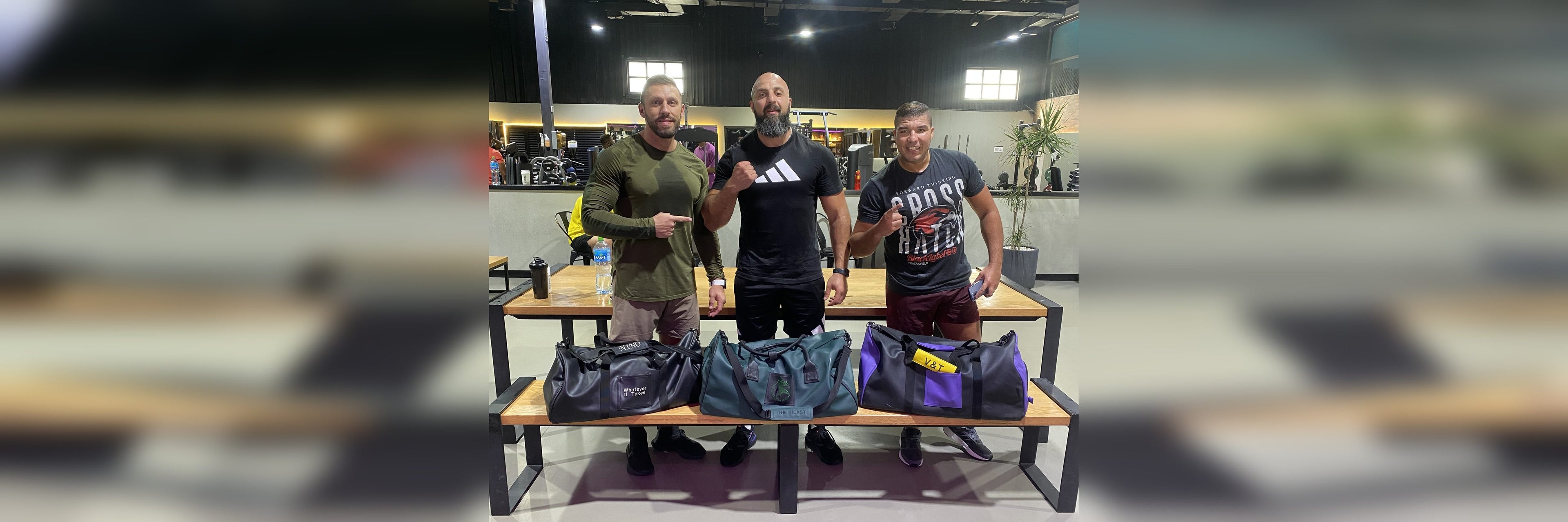 Three Dubai personal trainers with their custom YOUNfit duffel bags — homepage hero